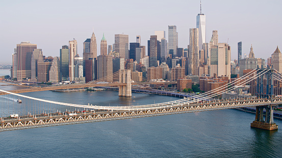 USA. NY. 09.20.2022. Beautiful panoramic view of Brooklyn Bridge over Hudson River and skyscrapers of Manhattan on against blue sky with white clouds.