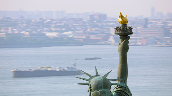 the statue of liberty with blurred american flag waving in the background. Democracy and freedom concept.