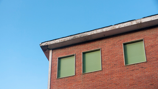 Green blinds window in brick building