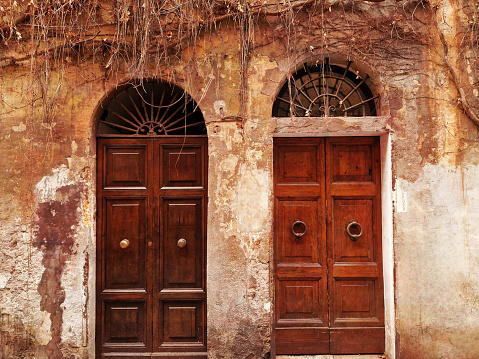 Arched old doors in weathered wall