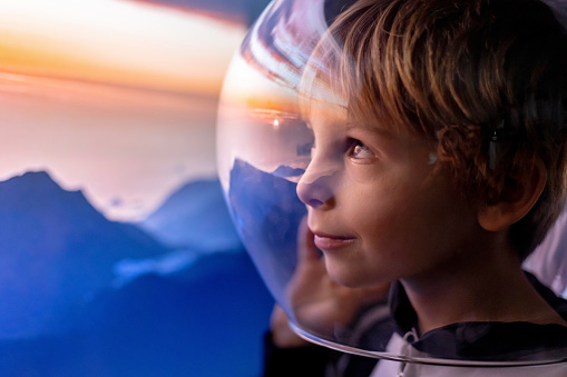 Cute child, boy, dreaming of becoming astronaut and flying into space. reflection of moon in his helmet