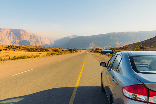 Dramatic view of beautiful mountain range and the rental car by the road in Oman, Middle East