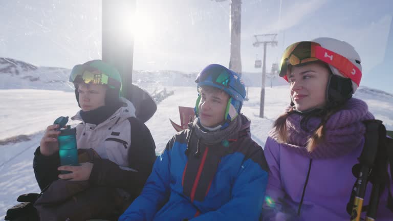 Teenagers enjoying gondola ski lift ride in Alps