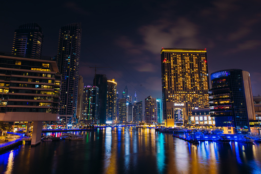 View of group of skyscrapers and yachts in the water during the night in Marina district of Dubai, United Arab Emirates