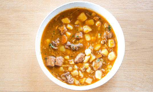 Traditional goulash soup with potatoes, carrots, beef on plate, ready to eat, directly above