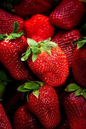 Pile of ripe organic red strawberries in foreground background