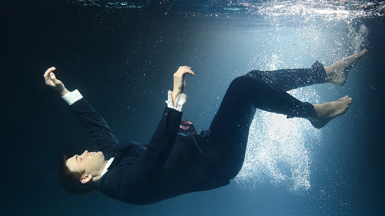 Businessman man in a suit, drowning under water