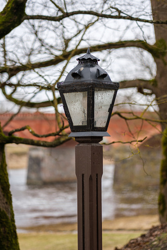 As dusk falls over Kuldiga, the lone lantern awakens, painting shadows of history upon the ancient streets of Latvija