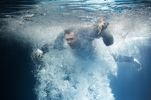 A businessman in a suit swims through the swirling current