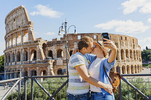 Happy woman and man tourist take a selfie at Rome Colosseum