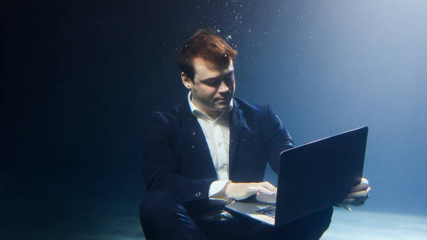 istock A businessman in a suit is working on a laptop underwater. 2086107905