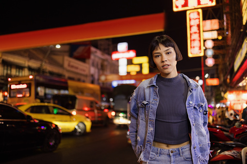 Portrait of Asian female tourist standing on the city street and night and looking at camera.