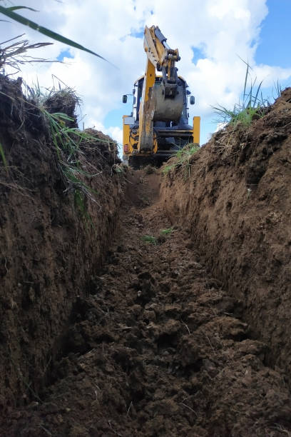 istock A yellow excavator digging a trench on the construction site, a close-up, against the sky. 2086124875