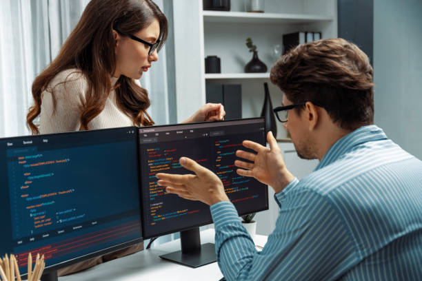 istock Woman standing opposite to man programmer working on desk to discuss. Postulate. 2086135004