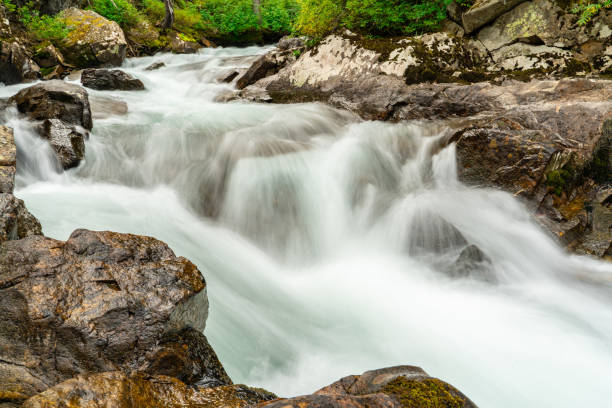 istock a waterfall in the wilderness with large rocks and trees surrounding 2086144970
