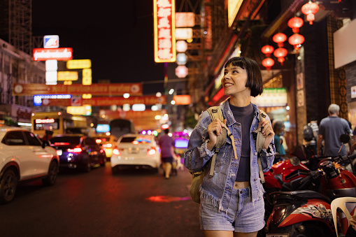 Young Asian female tourist enjoying while walking through the city street at night.