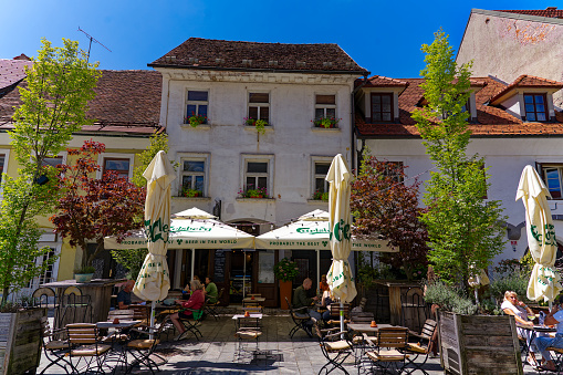 Old town of Slovenian City of Kranj with people sitting at restaurant terrace with plant pots decoration on a sunny day. Photo taken August 10th, 2023, Kranj, Slovenia.
