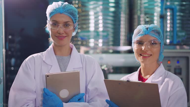 Portrait of Caucasian industry worker team work in factory warehouse. Attractive women industrial processing bottles of mineral water orders and food product at manufactory warehouse with happiness.