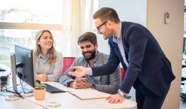 istock Small group of business people commenting computer's project and smiling at meeting around desk in the office. 2086230335