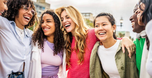 Multi ethnic group of young women hugging outside - Happy girlsfriends having fun laughing out loud on city street - Female community concept with cheerful girls standing together - Women  power