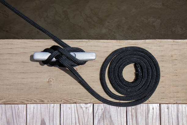 Close-up view of a yellow mooring bollard with a rope tied around it on a pier in Gdynia, Poland.