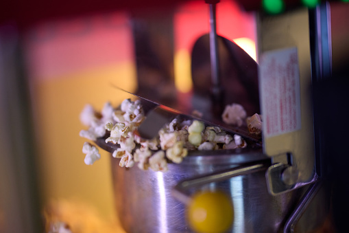 A close-up shot captures the mesmerizing process of making cinema popcorn, with kernels popping and releasing an irresistible aroma, promising a delightful snack for moviegoers.