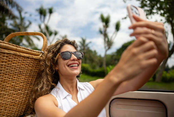 istock Woman on vacation taking a selfie while riding on a car 2086240817