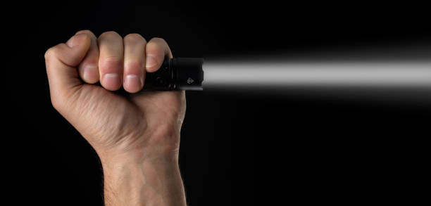 istock Black flashlight in human hands on a black background, including a white beam 2086242497
