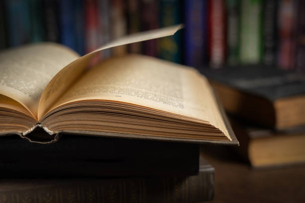 istock opened book, lying on the bookshelf in library 2086245731