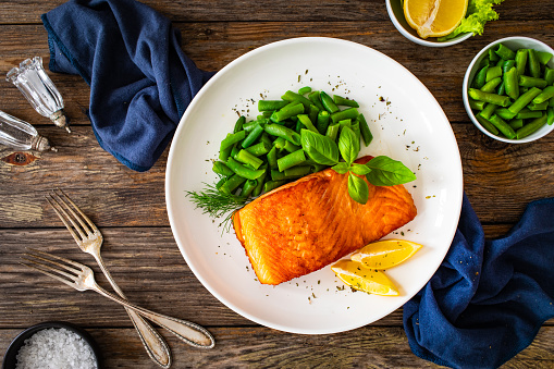 Seared salmon steak with boiled green bean on wooden table