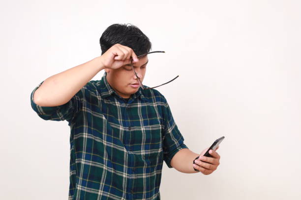 istock Sad young asian man standing while holding a cell phone. Isolated on white 2086258739