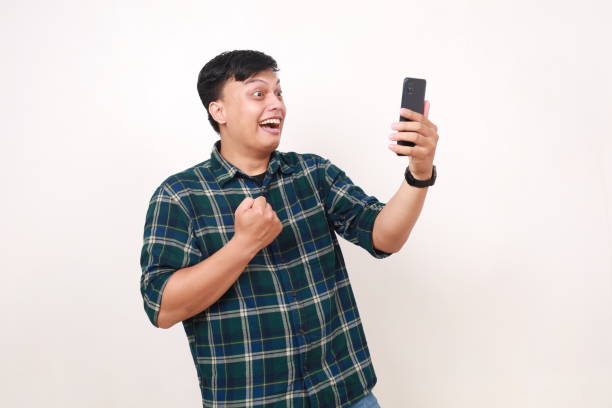 istock Wow surprised young asian man clenching his hand while holding a cell phone 2086262547