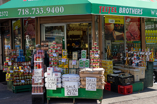 The Bronx, New York, USA – September 21th, 2023: Shop window and display on the sidewalk of a grocery store on Arthur Avenue in The Bronx New York. People can be seen in the store through the open shop door.