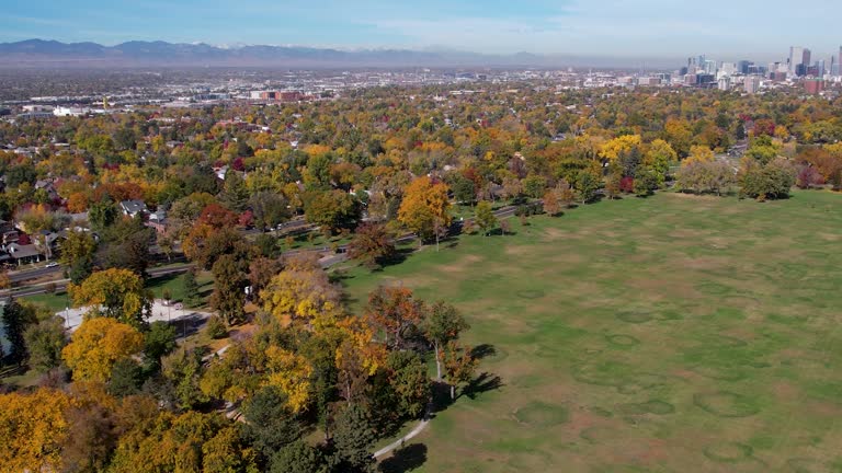 A 4K drone shot over Washington Park, with the Denver city skyline and the Rocky Mountain foothills in the distance, during the colorful Fall season in Colorado.