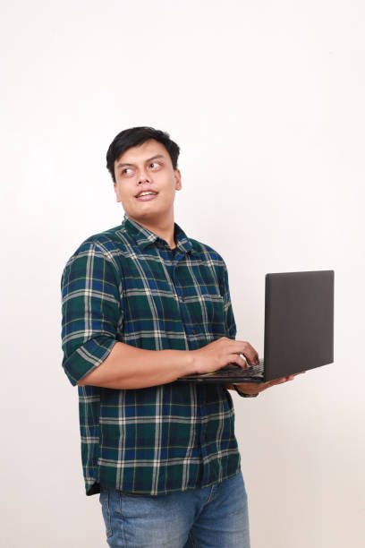 istock Young asian college student holding a laptop while looking behind 2086269115