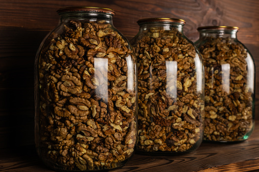 The walnut kernels in jar on wooden background..