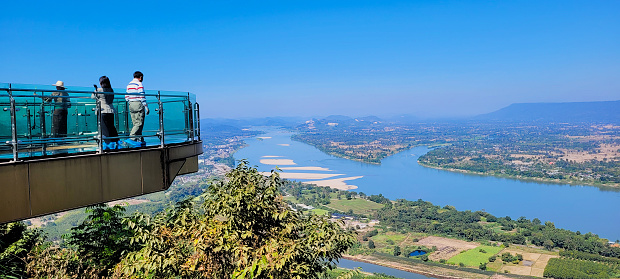 NongKhai,Thailamd-December 28,2023 : Tourist standing on skywalk of Phataksua temple to see view of Khong river the border between Thailand and Laos.