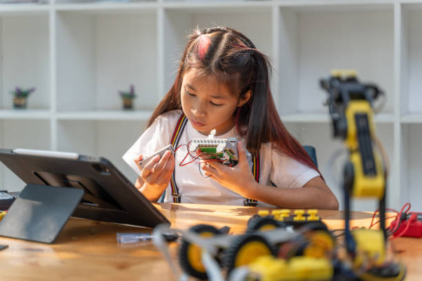 istock Smart young girl using small tool to put together her robot kit while following instructions from her computer tablet 2086282922