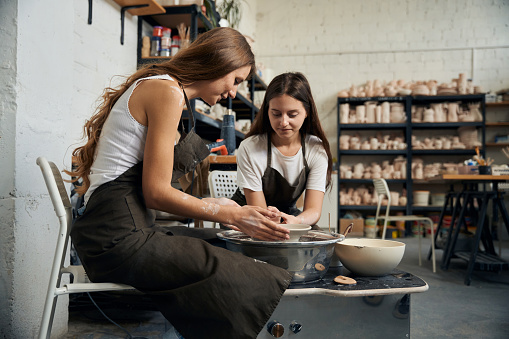 Women working with clay on a potter's wheel in masterful studio of ceramics works