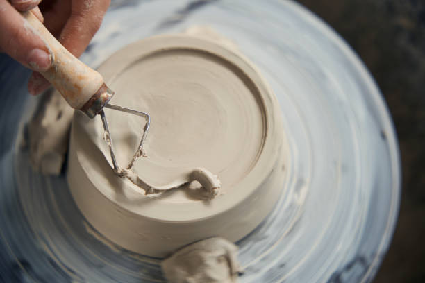 Unrecognizable woman ceramics working with pottery wheel and equipment in ceramics studio