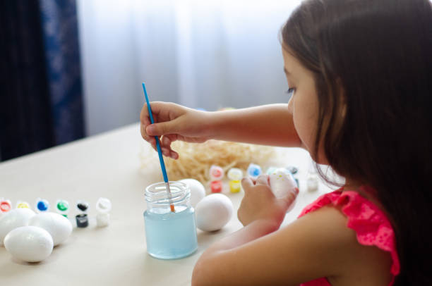 Girl painting eggs for Easter celebration.
