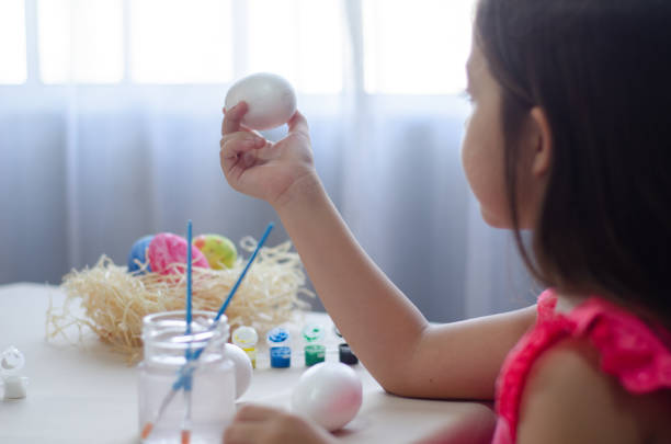 Girl painting eggs for Easter celebration.