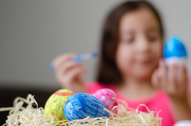 Girl painting eggs for Easter celebration.
