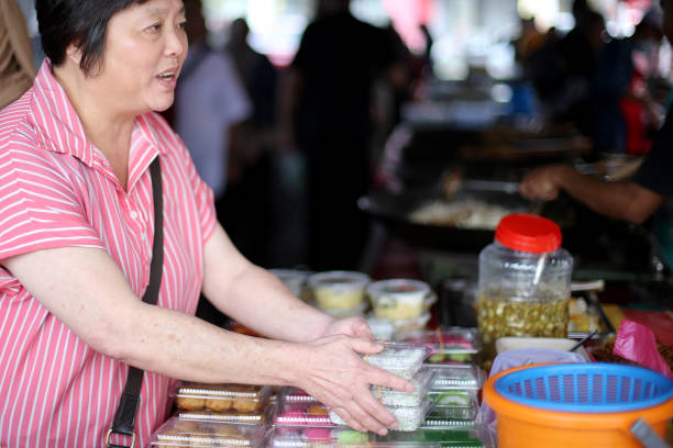 An Asian woman is shopping for food at street bazaar