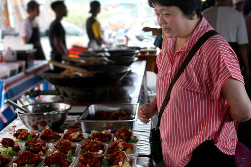 An Asian woman is shopping for food at street bazaar