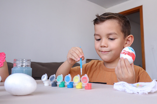 Boy painting eggs for Easter celebration.