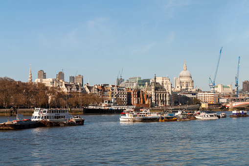 London, England - Aril 1, 2012: The River Thames with ships and boats and the city of london with St. Paul's Cathedral and buildings
