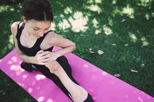 Smiling teenage girl doing yoga and stretching in backyard. Concept of healthy living and active lifestyle for younger generations.
