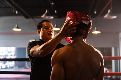 Referee explain rules and make preparation before give signal for the boxing match, boxer with safety helmet or head guard on the ring, ready to fight. Impetus