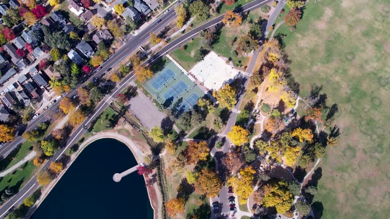 A 4K drone shot over Washington Park and Tennis Courts, Mount Vernon Garden, and Grasmere Lake, in Denver, Colorado, on a peaceful day, during the colorful Fall season.